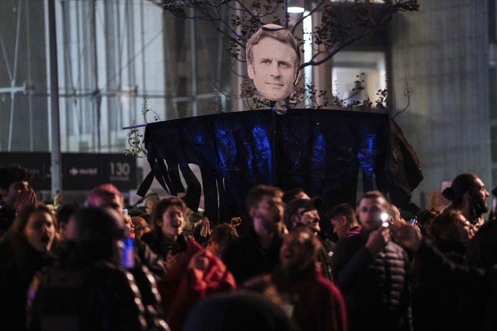 Protesters hold a banner with Emmanuel Macron's face during a protest in Paris, Saturday, March 18, 2023. A smattering of protests against President Macron’s plan to raise France's retirement age from 62 to 64 took place Saturday in Paris and beyond, as uncollected garbage reeked in the streets of the French capital amid a strike by sanitation workers. (AP Photo/Lewis Joly)