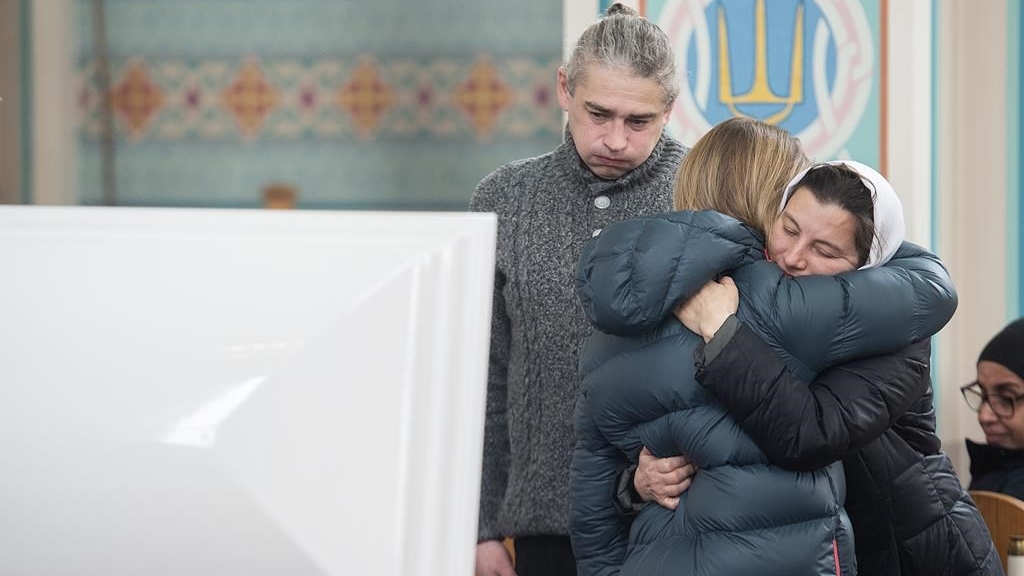 Des gens s'enlacent aux funérailles de la petite Mariia Legenkovska, 7 ans, happée mortellement en marchant vers l’école par un automobiliste qui a ensuite pris la fuite, le 13 décembre 2022 à Montréal.