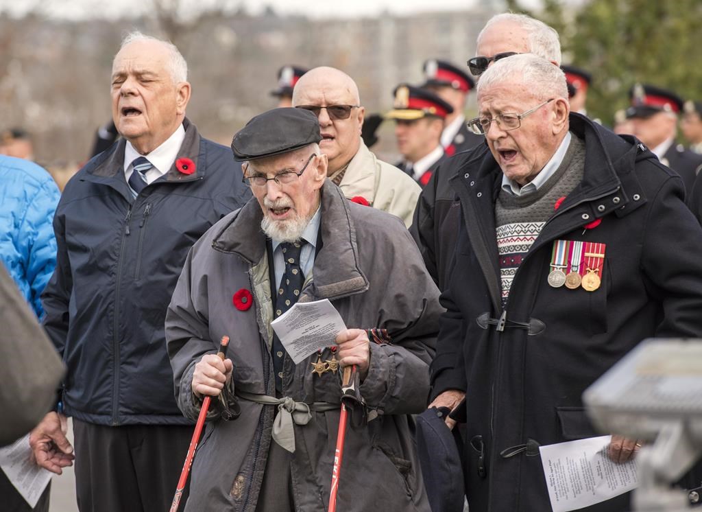 100-year-old Second World War veteran Angus Hamilton, centre, and Rev. Bob Jones, right, sing O Canada as part of the provincial Remembrance Day ceremony in Fredericton, Friday, Nov. 11, 2022. Three days before Hamilton turned 101, the Second World War veteran died peacefully at his home. THE CANADIAN PRESS/Stephen MacGillivray