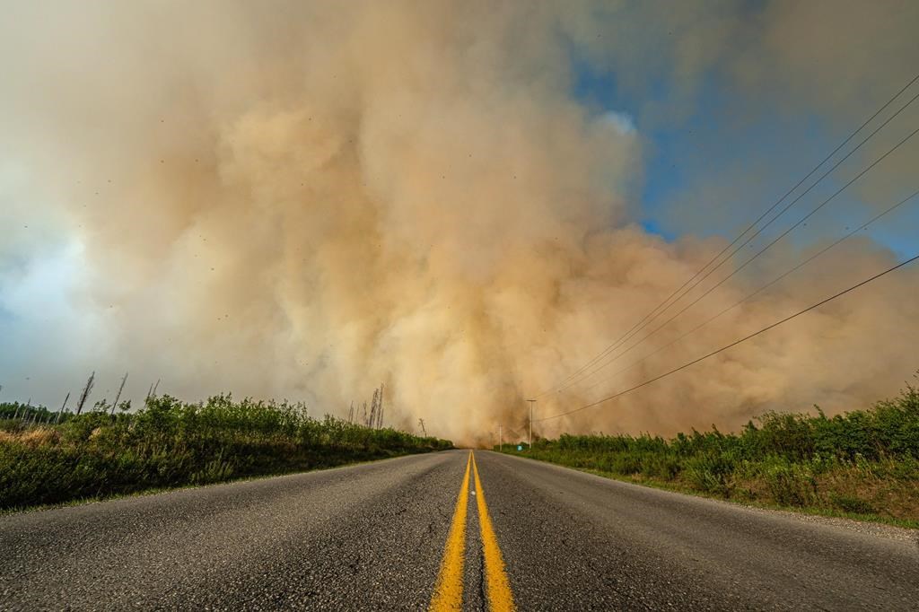 Smoke from a wildfire is shown crossing a road in British Columbia in this undated handout image provided by the BC Wildfire Service. A new out-of-control wildfire in British Columbia's Interior has sparked a mandatory evacuation order in area approximately 600 kilometres north of Vancouver.THE CANADIAN PRESS/HO-BC Wildfire Service **MANDATORY CREDIT**