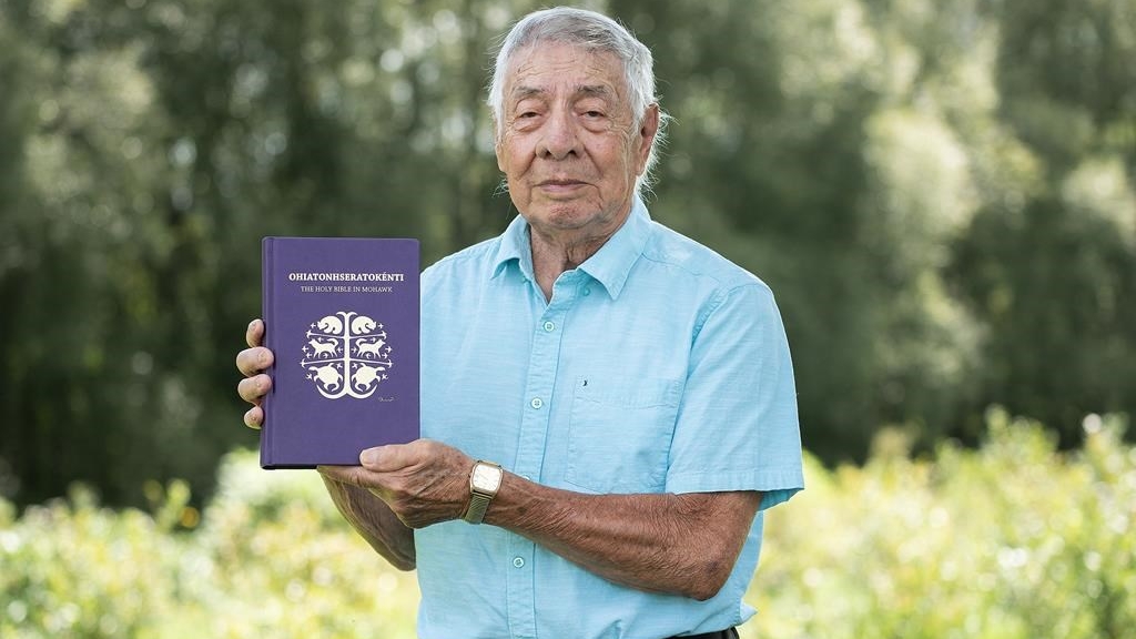 Harvey Satewas Gabriel pose avec une copie de la Bible qu'il a traduite de l'anglais au mohawk à son domicile de Kanesatake, au Québec, le 27 août 2023.