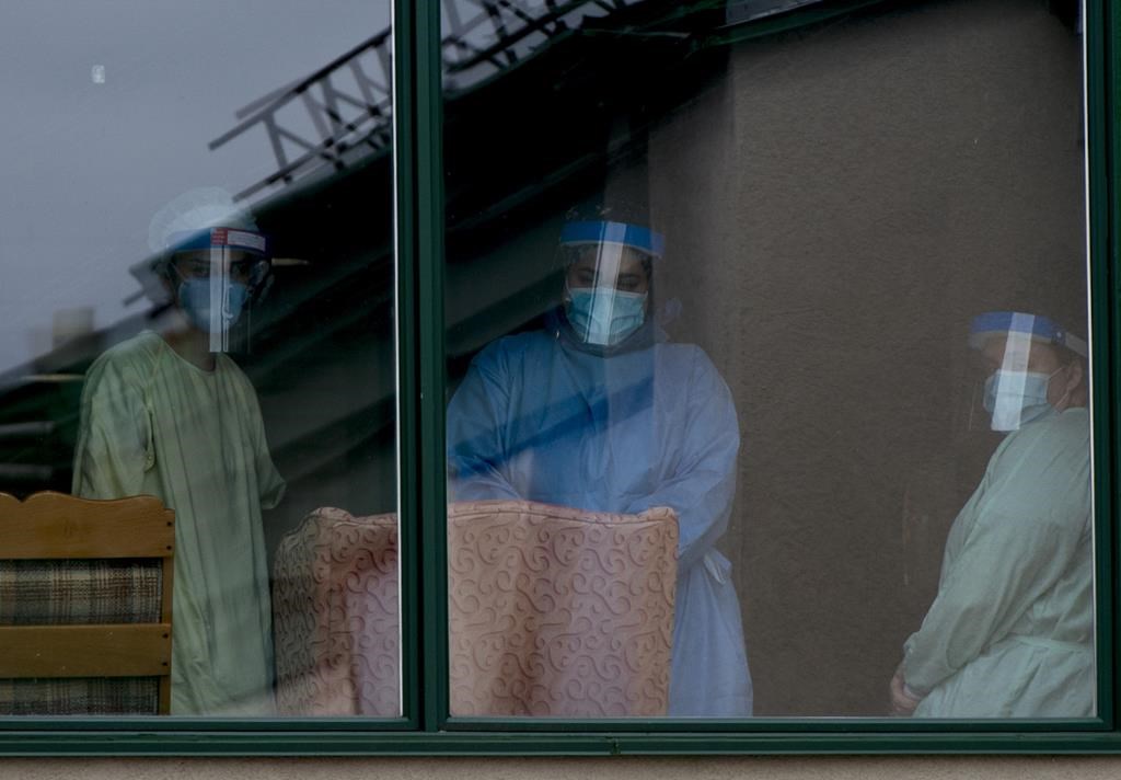 Health-care workers look out from a long-term care home in the Montreal suburb of Dorval, Que., on Saturday, April 11, 2020. A Montreal lawyer says Quebec's initial response to the risk of COVID-19 to long-term care residents was marked by improvisation. THE CANADIAN PRESS/Graham Hughes