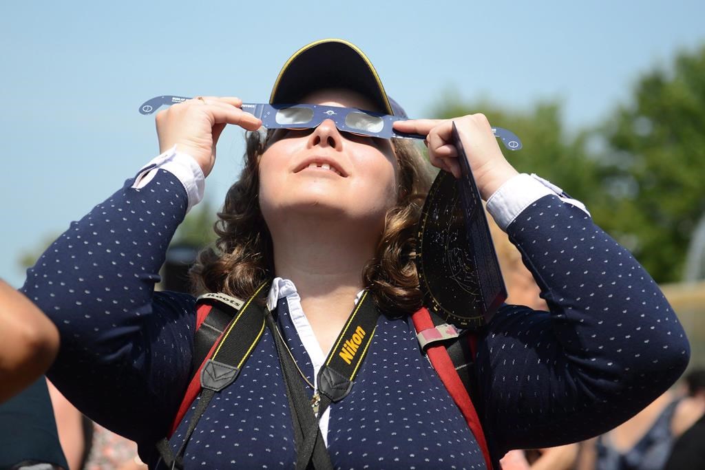 Des observateurs regardent une éclipse solaire à l'Exposition nationale canadienne à Toronto, le lundi 21 août 2017.