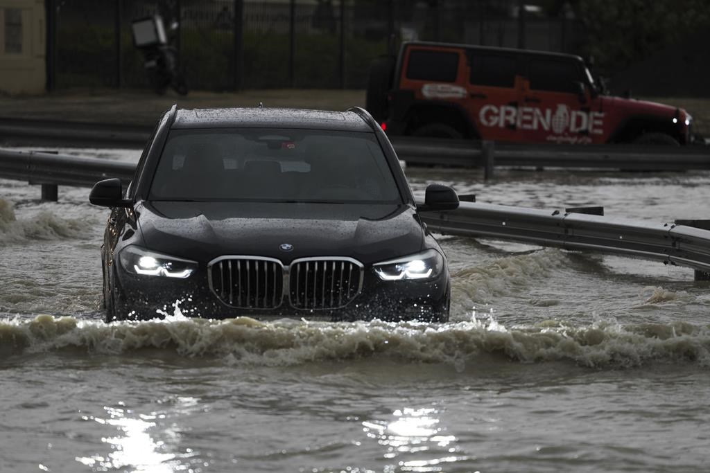 An SUV stalls out while trying to pass through standing water in Dubai, United Arab Emirates, Tuesday, April 16, 2024. Heavy rains lashed the United Arab Emirates on Tuesday, flooding out portions of major highways and leaving vehicles abandoned on roadways across Dubai. Meanwhile, the death toll in separate heavy flooding in neighboring Oman rose to 18 with others still missing as the sultanate prepared for the storm. (AP Photo/Jon Gambrell)