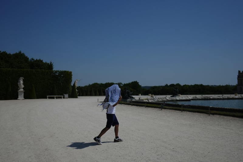 Un homme se protège du soleil à l’aide d’un foulard alors qu’il se promène dans le jardin du château de Versailles, près de Paris, pendant une vague de chaleur où les températures dépassent les 40 degrés Celsius (104 degrés Fahrenheit), le lundi 22 juin 2026.