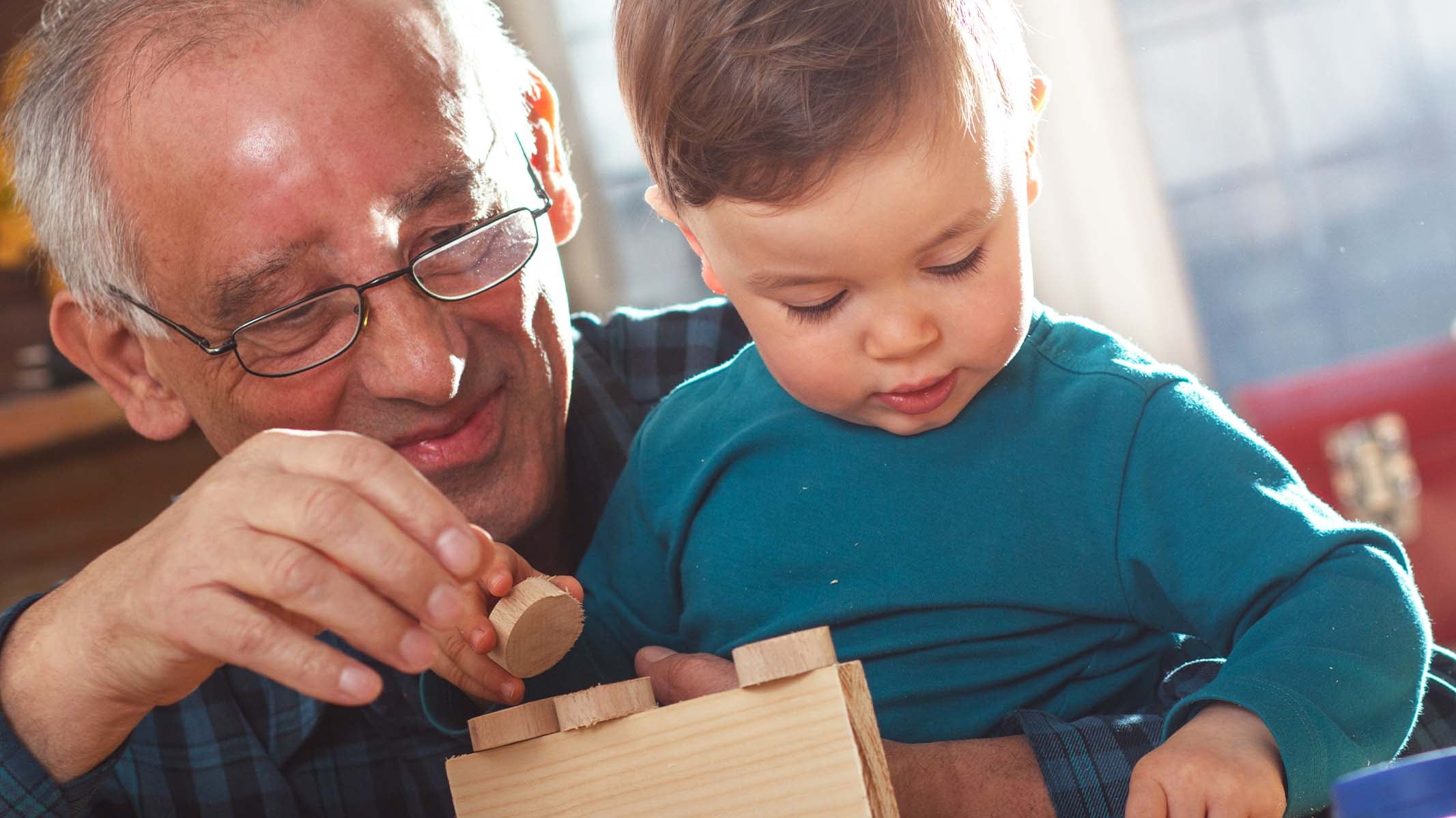 Un grand-père et son petit fils jouent avec des blocs de bois.